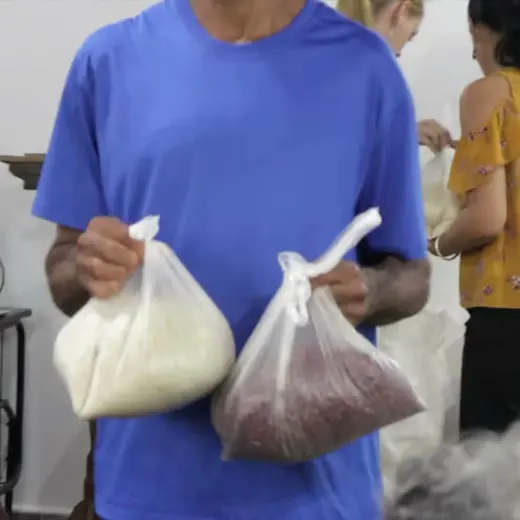 A man at a church holds up two bags of beans to hand out