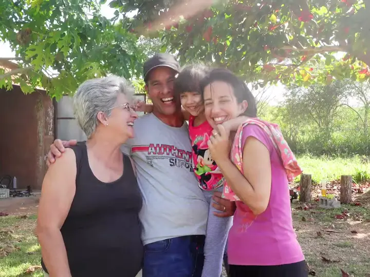 A grandmother, father, mother and little girl in Cuba laughing together outside their home