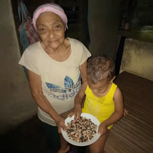 A grandmother and a small child hold a plate of beans